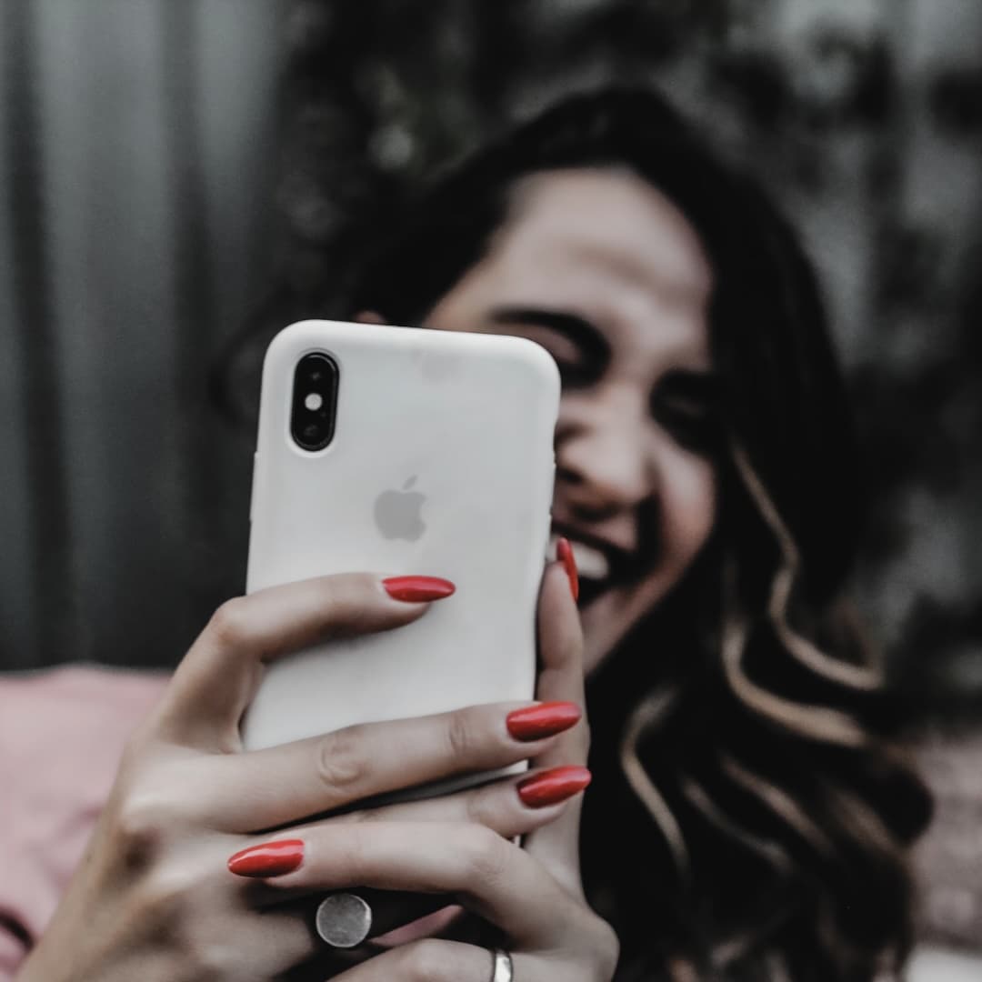 Smiling woman holding a smartphone with the Baba Yaga Cycle Coach app—representing joyful body literacy and a safe period tracker app experience.